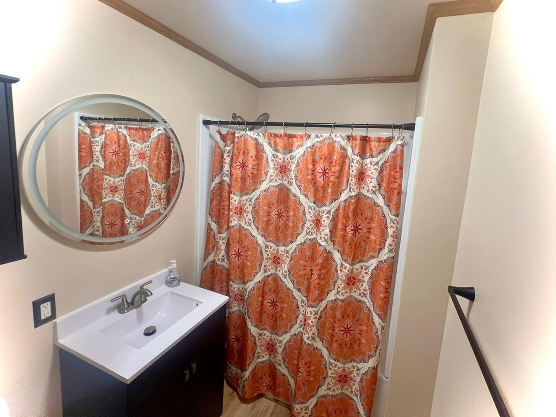 Refreshed bathroom with smooth painted walls, a black vanity and a round lighted mirror