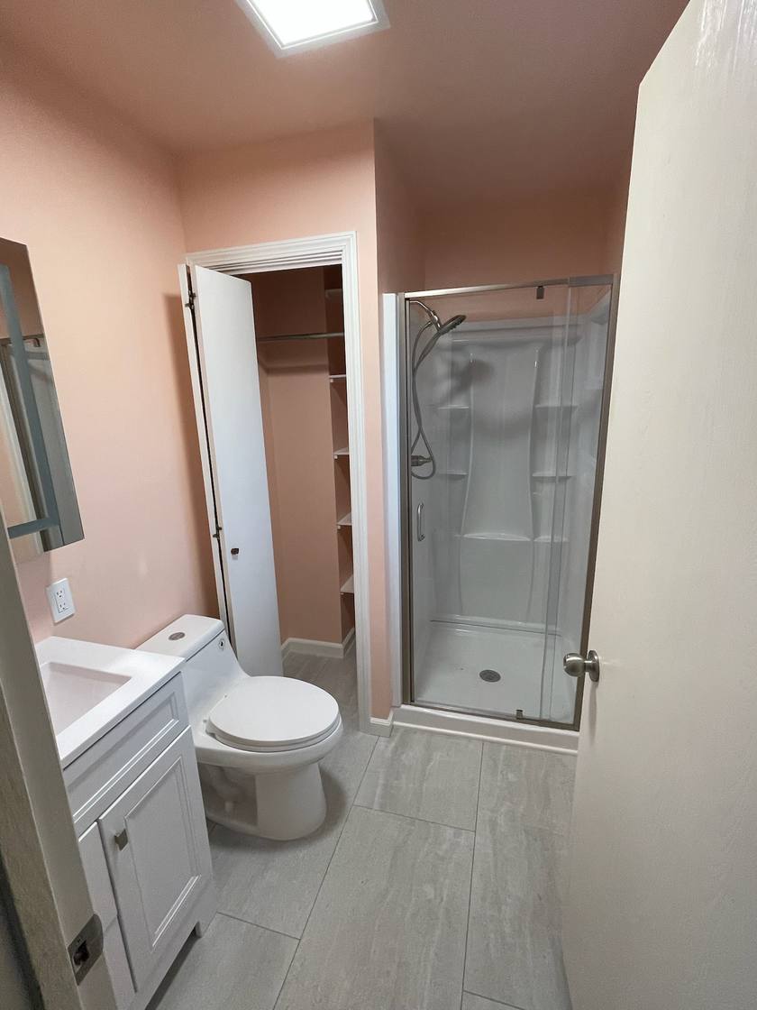 Finished bathroom with a new glass-door shower, tile floor, white vanity and closet