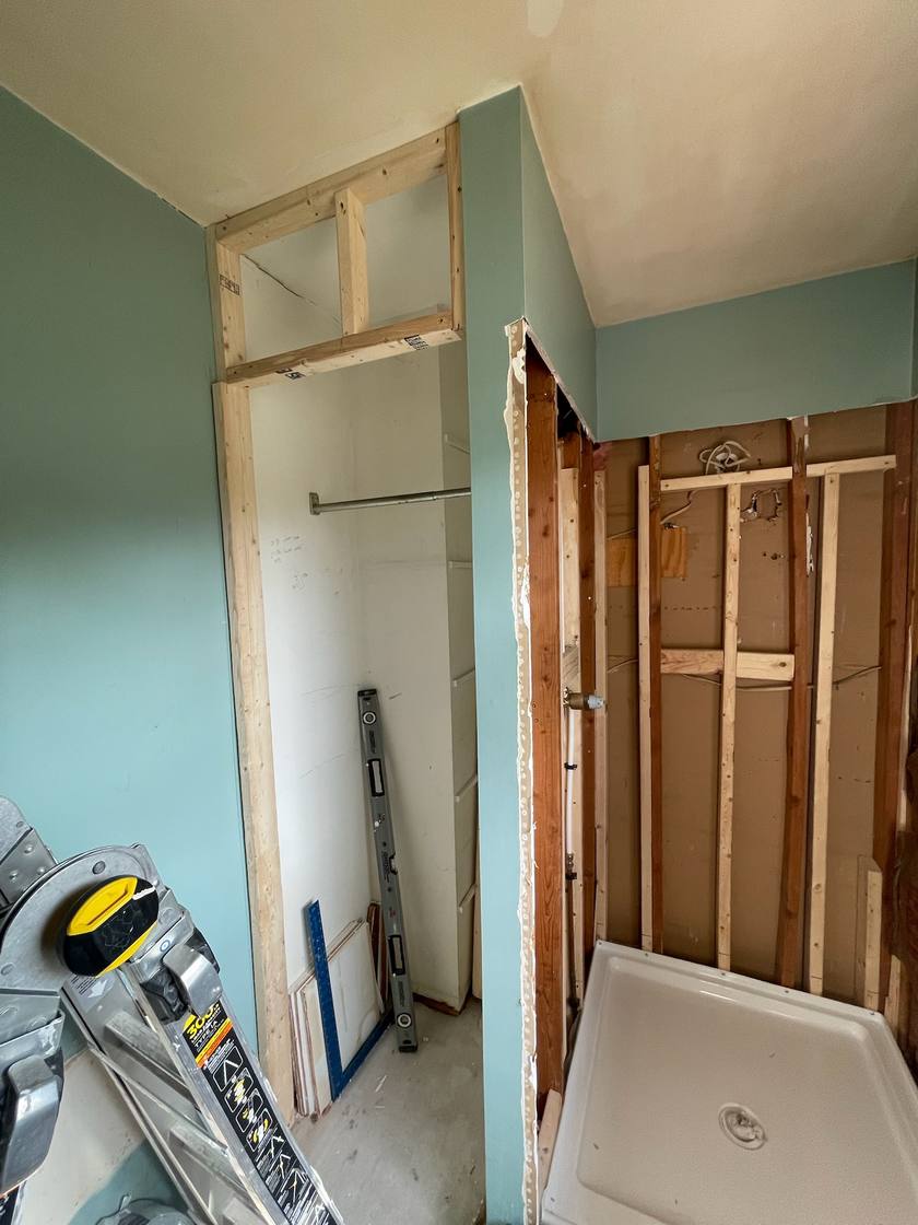 Bathroom mid-remodel, with the new shower base set and the closet framed in