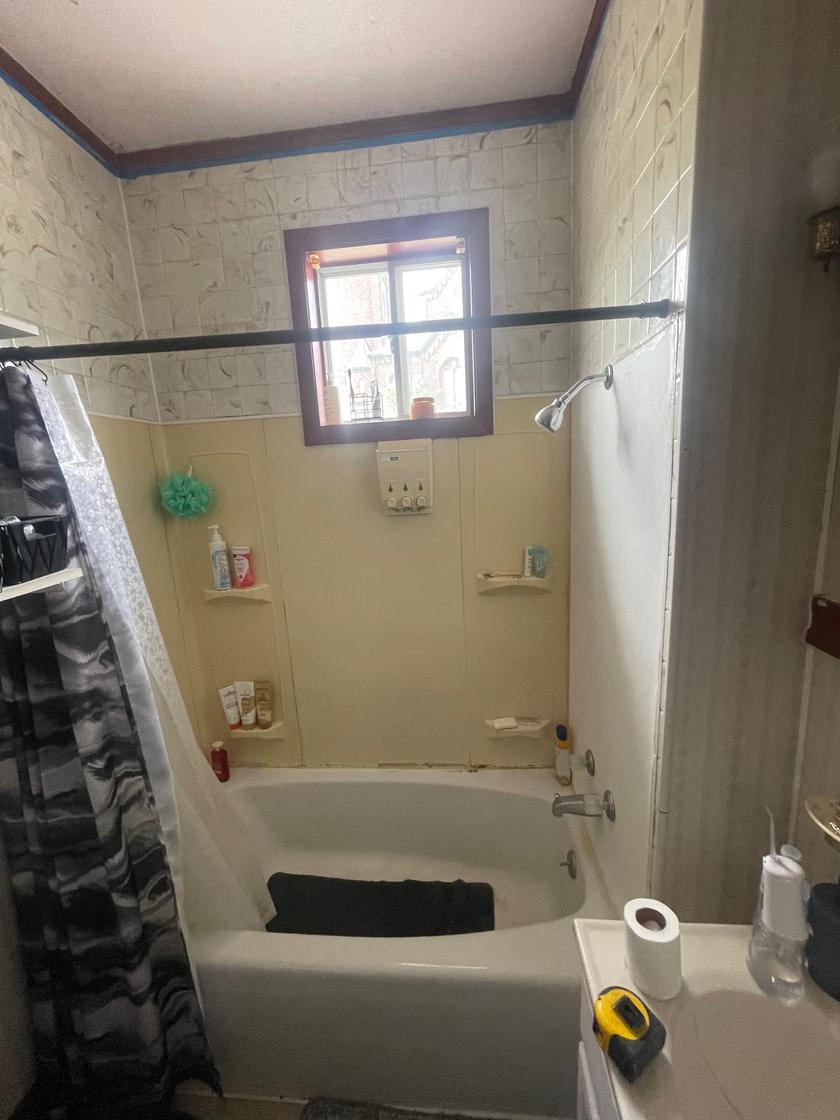Bathroom before the remodel, with a fiberglass tub surround and old wall tile
