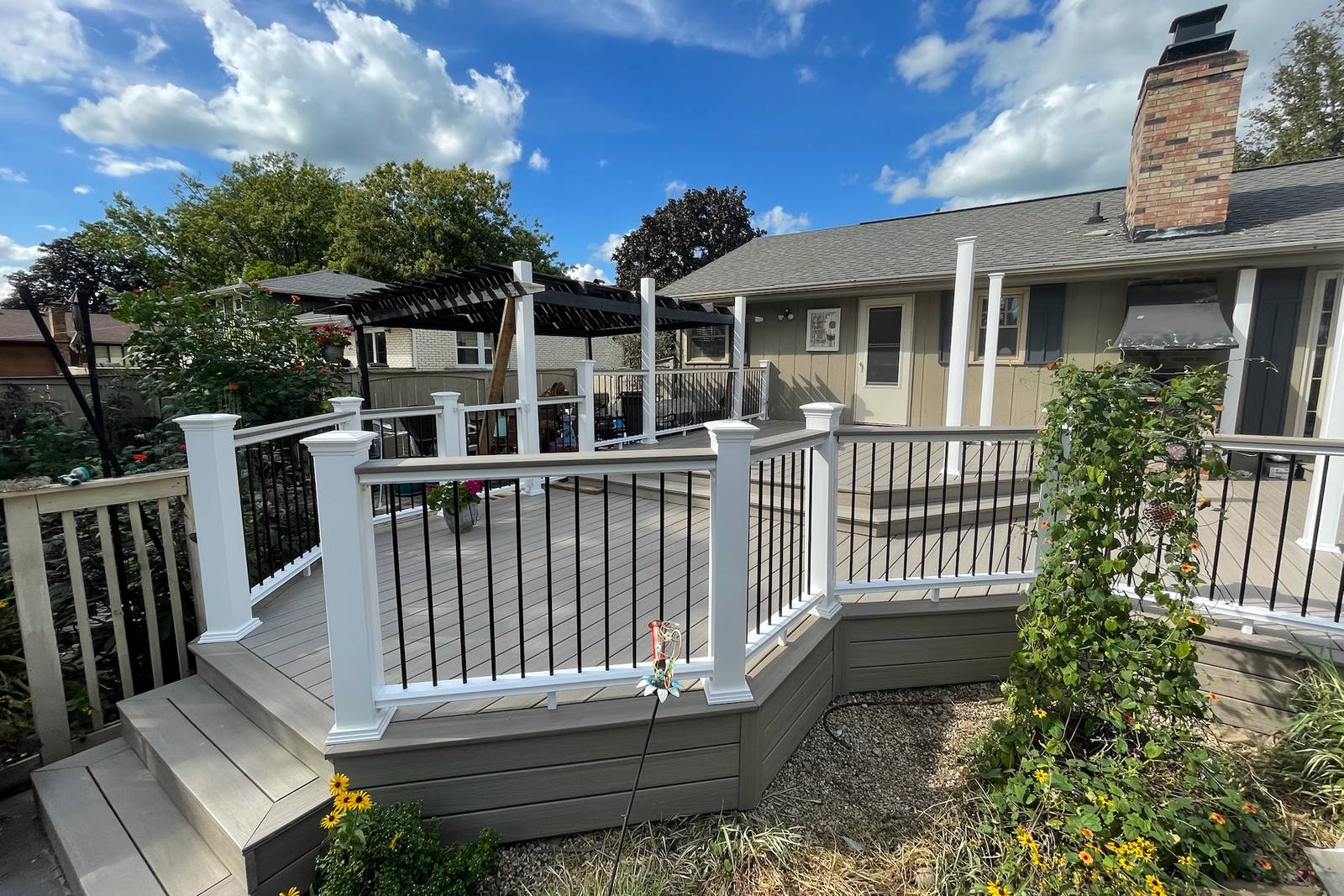 Multi-level composite deck with white posts, black balusters and wrapped stairs